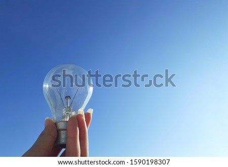close up photo of a hand holding a fluorescent light bulb with sky in background