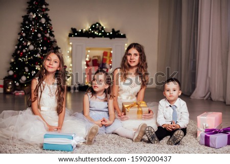 the little boy and three girls open Gifts Christmas new year tree Garland