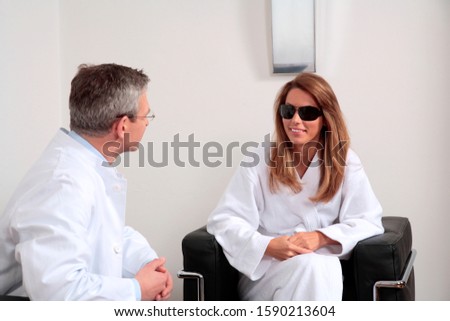 Plastic surgeon talking to patient wearing sunglasses