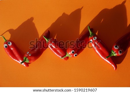 Sweet Small Red Peppers. Funny faces with wobbly eyes. Zigzag, Fire Red And Orange Red Colors Background.