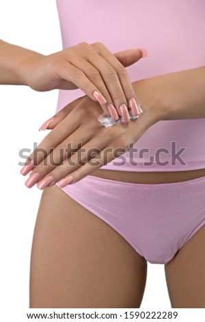 Close up of woman in underwear applying moisturizer to hands