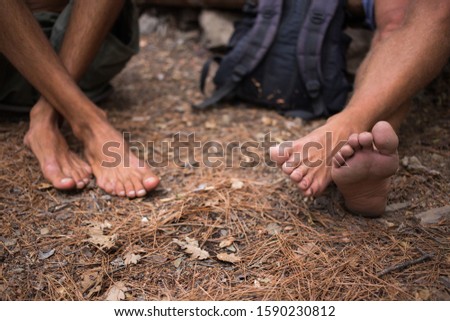 Two people sitting on the ground. Bare feet.