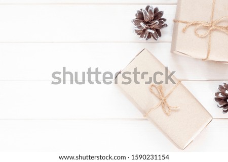 Christmas card. Gifts in craft packaging on white wooden background. Copy space