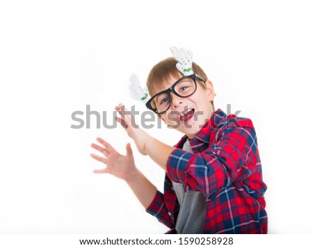 
boy in stylish clothes in a red cage shirt with funny glasses rejoices, dances and sings, rejoices in the New Year and Christmas on a white background Royalty-Free Stock Photo #1590258928