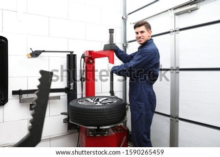 Man working with tire fitting machine at car service
