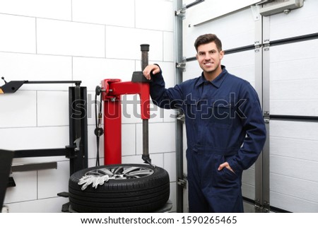 Man near tire fitting machine at car service