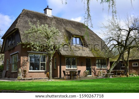 landscape and view of Giethoorn village in Netherlands (Holland) near Amsterdam, canal boat trip and old typical and traditional vintage thatched houses (cottage), famous attraction, destination.  Royalty-Free Stock Photo #1590267718