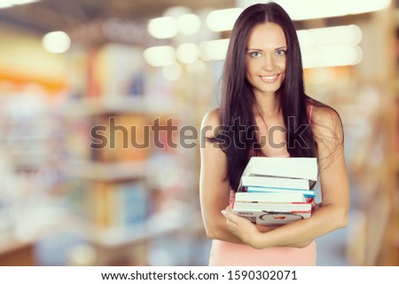 Smiling woman holding books on abstract background