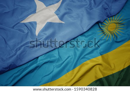 waving colorful flag of rwanda and national flag of somalia. macro