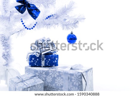 Beautiful New Year presents in silver blue color stand under the Christmas tree on a white background. Concept of artificial christmas tree as environmental protection. Advertising space
