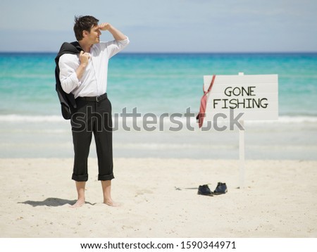 Businessman next to Gone Fishing sign at beach