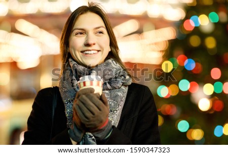 Picture of young woman with glass in hands on blurred background with burning garlands