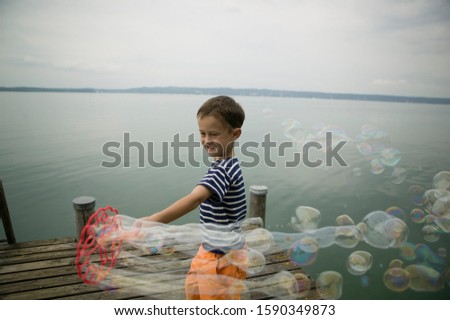 Young boy making bubbles near lake