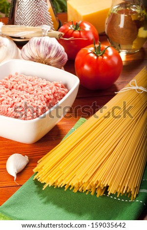 Spaghetti, tomatoes and raw meat on wood 
