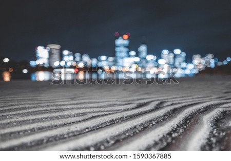 The patterns on the sand by the river with the blurred buildings in the background