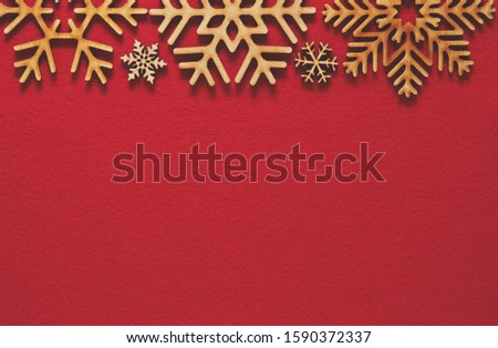 Red flat lay Christmas background with handmade wooden snowflakes. Rustic decorations for winter holiday wallpaper design with empty space for text. New Year celebration poster template