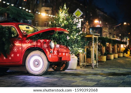 Retro car with gift boxes and christmas tree on night street in  Paris. Christmas and New Year street decoration festive lights, bokeh in the evening. 