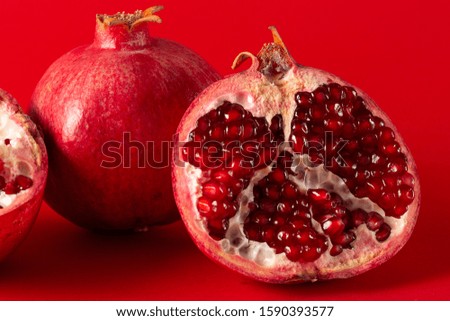 Ripe pomegranates with whole pomegranate isolated on a red background.