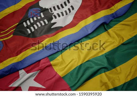 waving colorful flag of togo and national flag of swaziland. macro