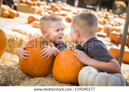 Two Boys at the Pumpkin Patch Talking About Their Pumpkins and Having Fun on a Fall Day. 