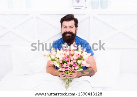 good morning flowers. Flowers are Perfect Pick-Me-Up to Boost Morning Mood. morning people concept. positive mood and happiness. happy bearded man in bed. birthday gift bouquet. spring fresh tulip.