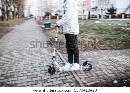 man rides a white electric scooter on a frosty winter day. Electric transport.