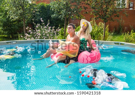 Ecology concept - Young man and woman having fun while the environment is polluted, concept of global problem with plastic rubbish floating in the water.