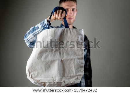 hand holding a blank monocolor textile cotton bag with copy space, design for text