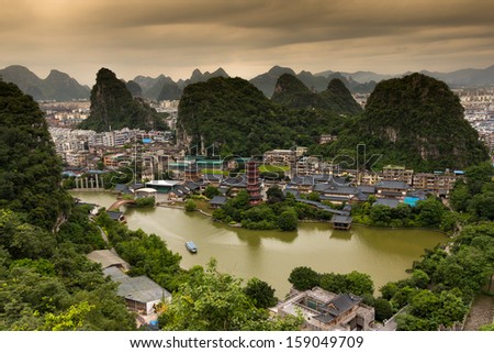Lookout over Guilin City in SouthProvince, South China. Peacful Atmosphere in the morning. Sunrise behind the mountains. Boat in the lake. Ancient Pagoda in the middle, center of the picture.