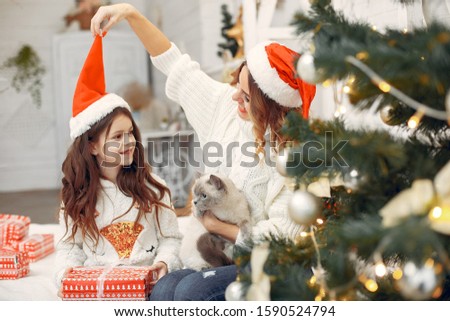 Beautiful mother in a white sweater. Family with cristmas gifts. Little girl in a santas hat