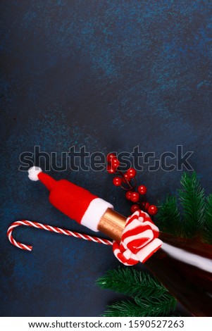 Christmas concept. Bottle of champagne in a red santa hat with spruce branches on a dark blue background. top view, flat style, place for text