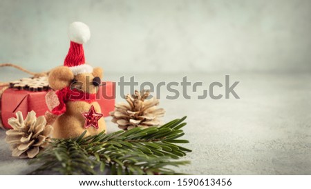 Little toy Christmas mouse, gift and decorations on a gray table. Christmas composition with the symbol of 2020 according to the Chinese horoscope