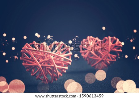Romantic composition - two wicker hearts symbol of love and lights on a dark table. Valentines day concept