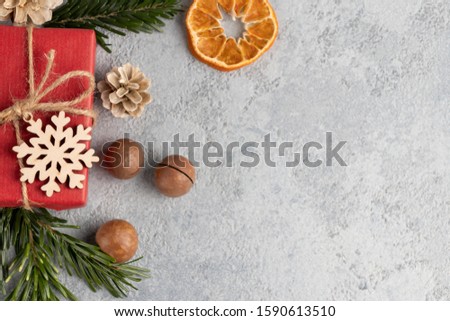 Christmas or New Year gray background with decorations from natural materials - Christmas tree twigs, nuts, cones, wooden snowflake and dried orange