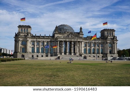 Berlin capital building, blue sky green grass and German flags blowing in the wind. Translation "[To] the German people"