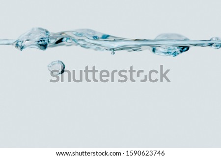 Studio shot of a small water wave with a single rising bubble against white background.