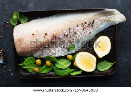 Fresh cod fillet of white sea fish before cooking with sea salt, olive oil, herbs and pepper. Healthy eating concept,