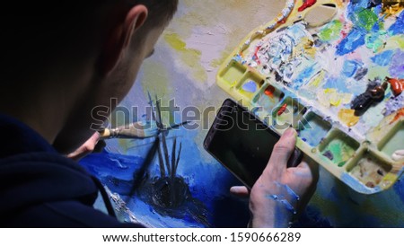 Artist copyist paint seascape with ship in ocean. Craftsman decorator draw as boat sail on blue sea with acrylic oil color. Draw finger, brush, knife palette. In hand of cellphone tablet computer pc.
