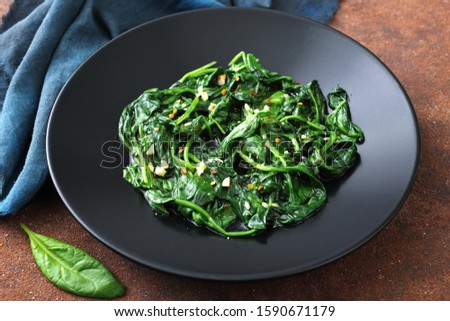 vegetarian food cooked spinach in black dish  Royalty-Free Stock Photo #1590671179