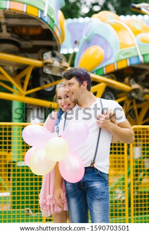 Happy cheerful smiling loving couple hugging and holding balloons in the amusement Park