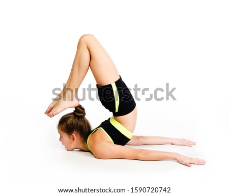 Flexible cute little girl child gymnast doing acrobatic exercise isolated on a white background. Sport, training, fitness, active lifestyle concept