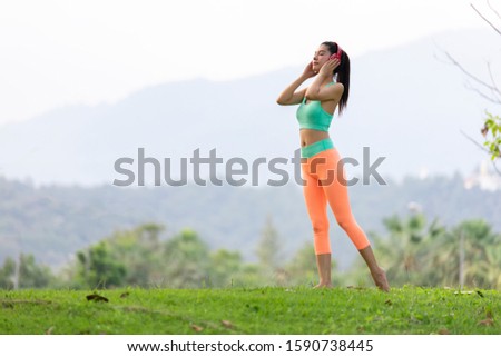 Asian woman sporty listening to the music on headphones in gaden.