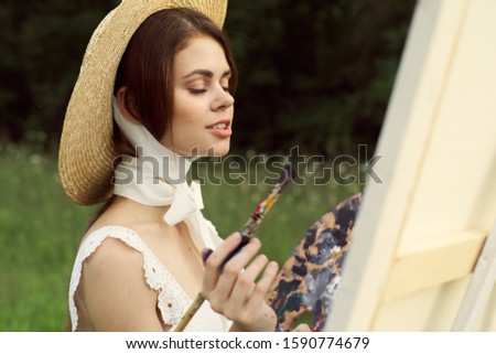 young woman in a straw hat draws pictures