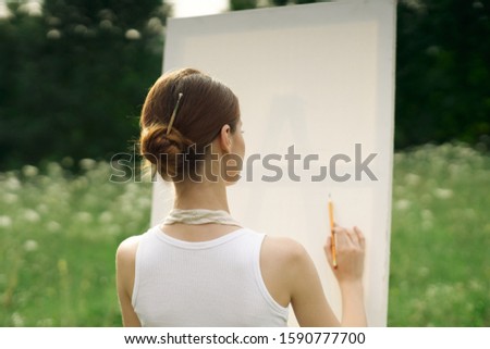 young woman draws on canvas outdoors