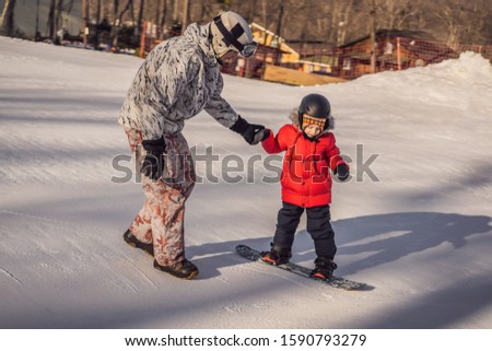 Dad teaches son snowboarding. Activities for children in winter. Children's winter sport. Lifestyle