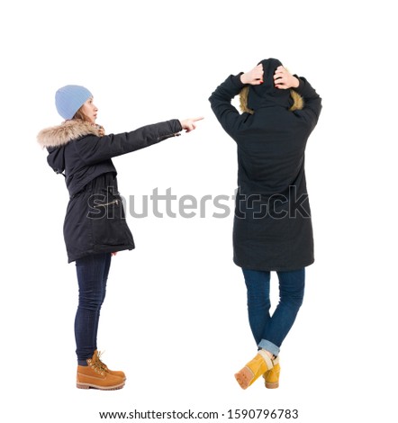 Back view of two pointing young girl in winter jacket. Rear view people collection.  backside view of person. beautiful woman friends  showing gesture. Rear view. Isolated over white background. 
