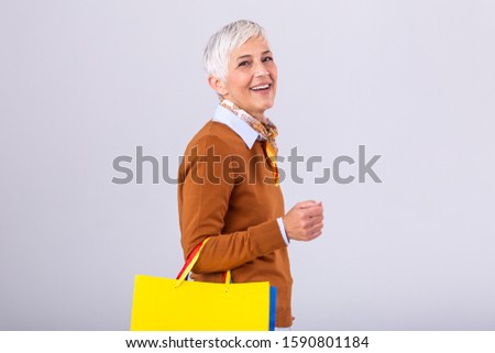 Portrait of a happy mature woman holding shopping bags and looking at camera isolated over white background