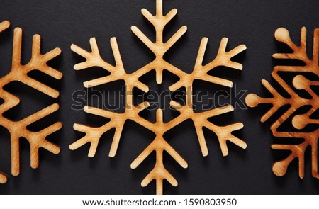 Decortive wooden snowflake in flat lay on black background for Christmas party wallpaper design.Handmade rustic toys made from ecological wood material.Home decoration for New Year celebration event