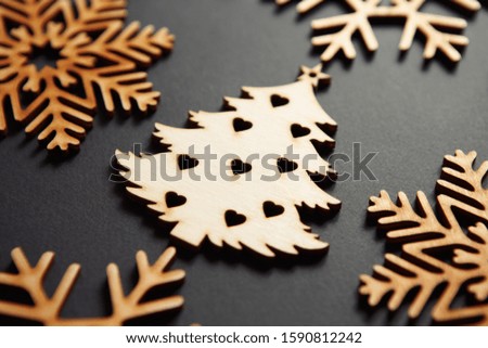 Beautiful handmade wooden Christmas tree toy on black background shot in close up.Decorative rustic elements for winter holidays 
