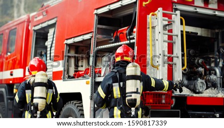 Group of Fireman in action. Firefighter in uniform, fire brigade team work